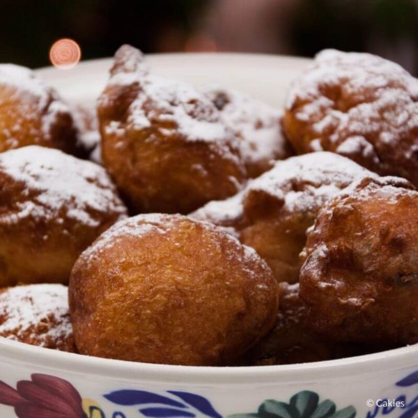 oliebollen in a bowl dusted with confectioners' sugar